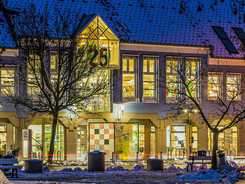 Außenansicht der Stadtbücherei Tettnang im Dunkeln mit beleuchtetem Eingang.