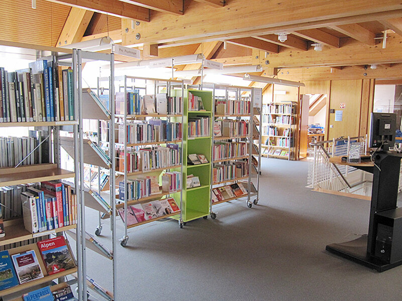 Moderne Regale mit Büchern und breiter Durchgangsbereich in der Bibliothek.